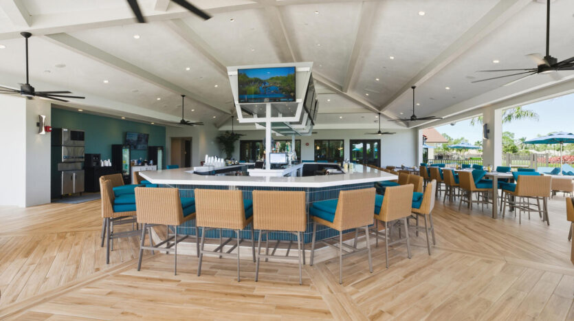 Modern bar area with high chairs and a TV screen in a spacious room.