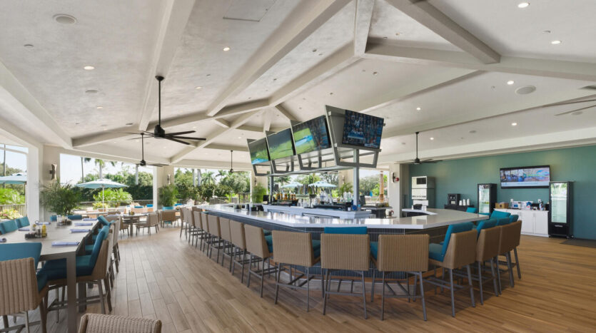 Modern bar with multiple screens and blue cushioned stools.