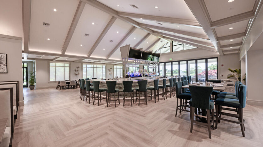 Modern bar area with high stools and large windows providing natural light.
