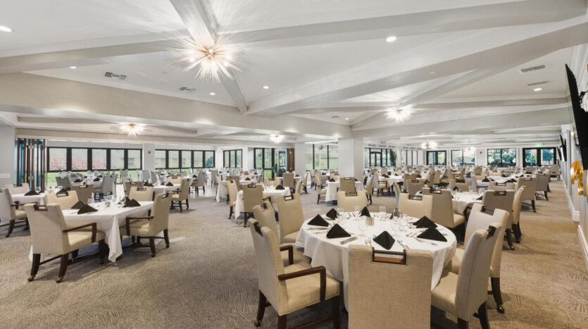 Elegant banquet hall with round tables and beige chairs.