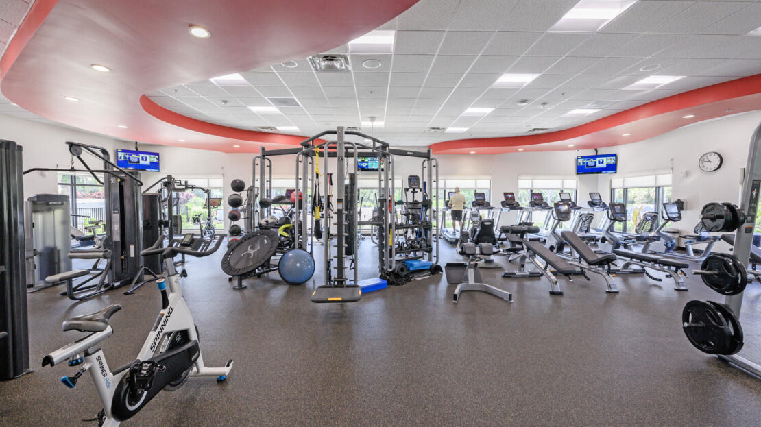 Spacious, modern gym with various exercise machines and equipment.