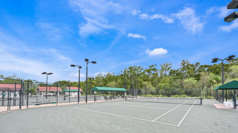 Empty outdoor tennis courts under a bright blue sky.